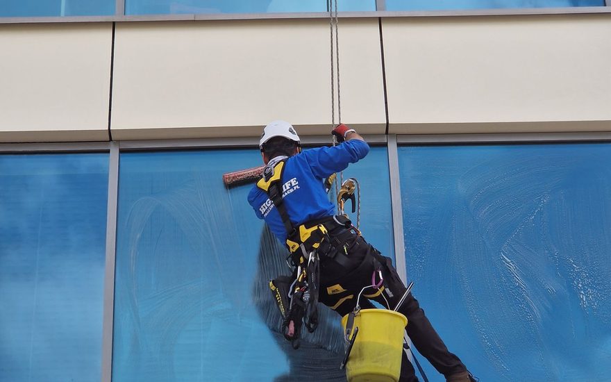 Rope access window cleaner on a blue glass tower