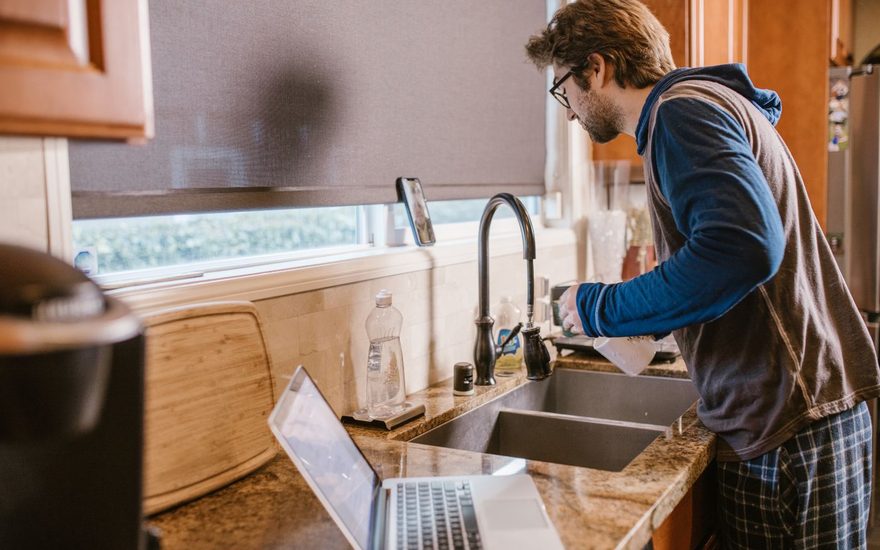Man washing up at a kitchen sink by the window