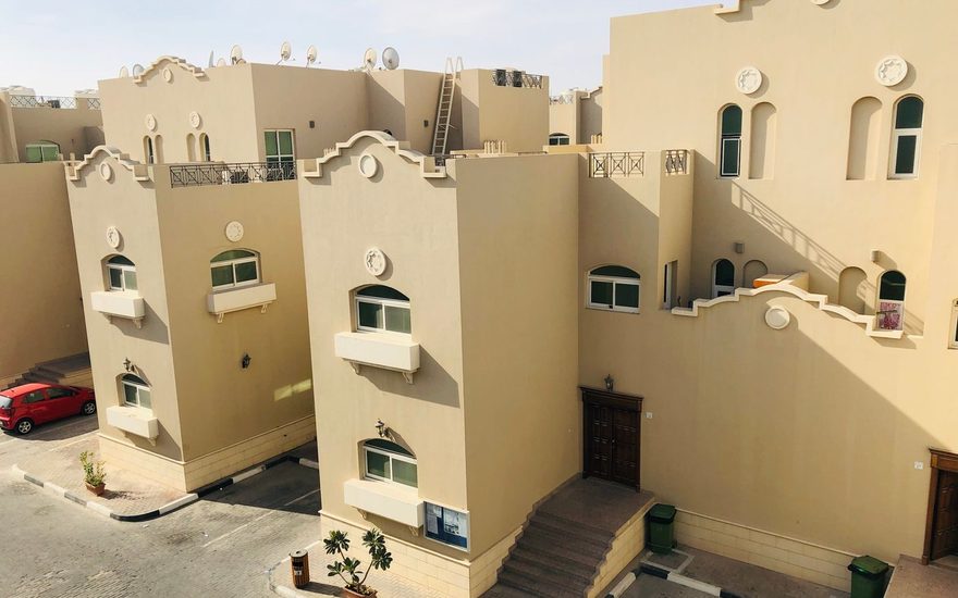 Beige low rise apartment buildings around a shared courtyard